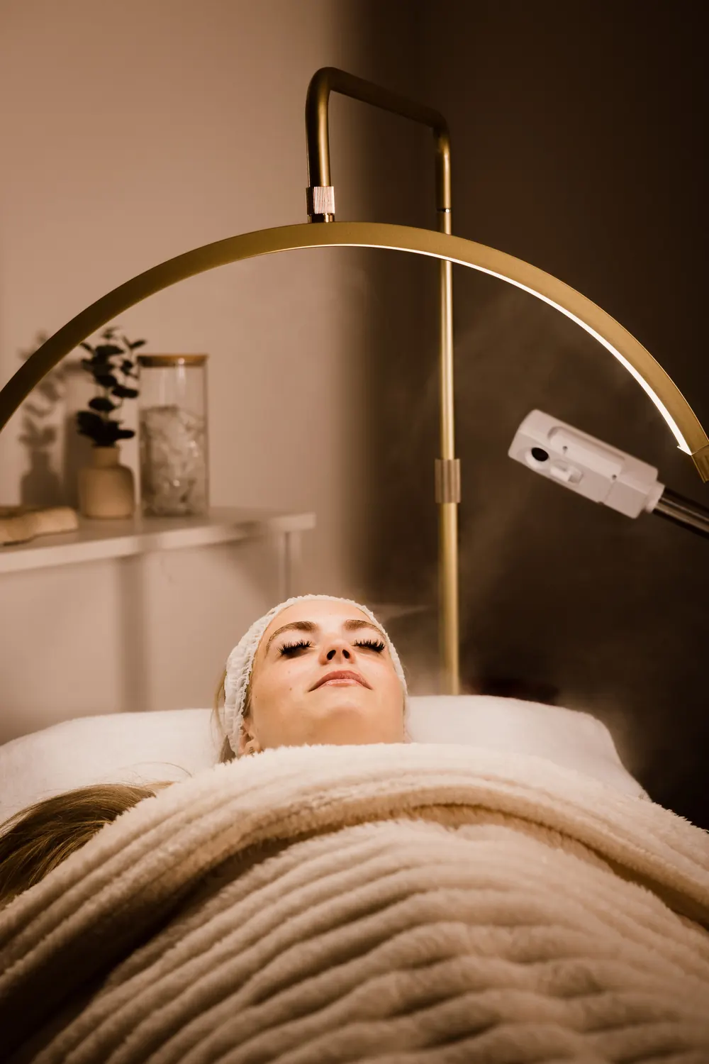 Calm aesthetics treatment room with a client relaxing under a blanket