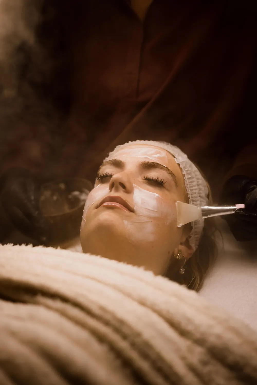 Close-up of a skincare mask being brushed onto a client’s face